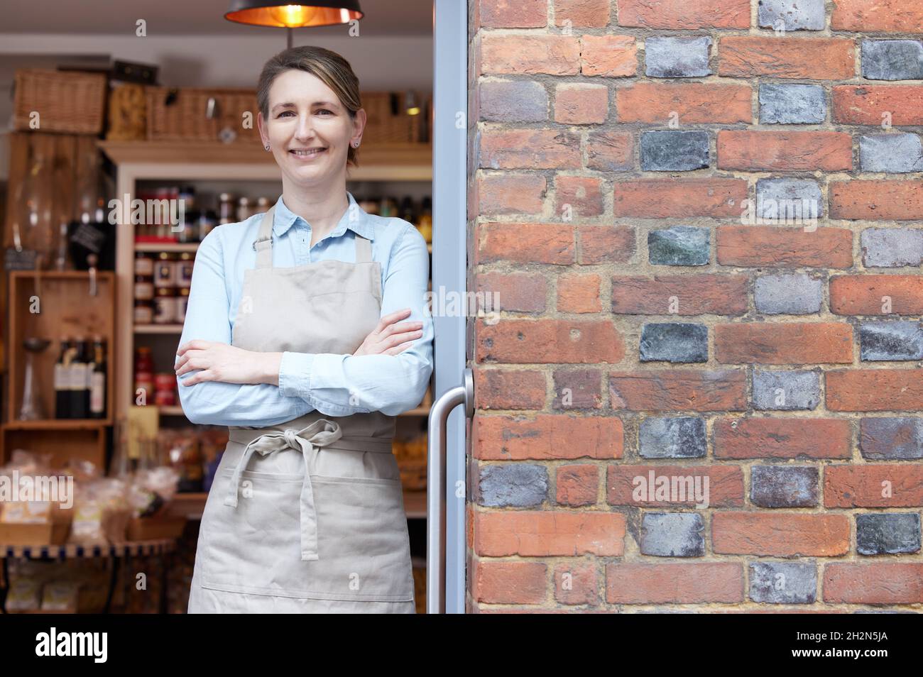 Porträt Einer Besitzerin, Die Im Doorway Of Delicatessen Food Steht Kaufen Stockfoto