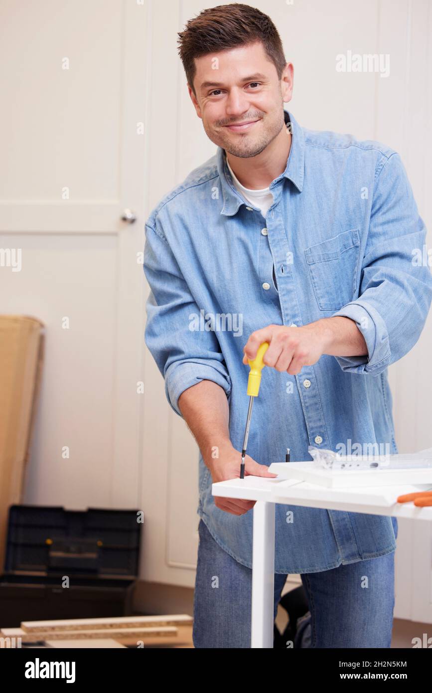 Portrait Of Man Putting Together Self Assembly Furniture At Home Stockfoto
