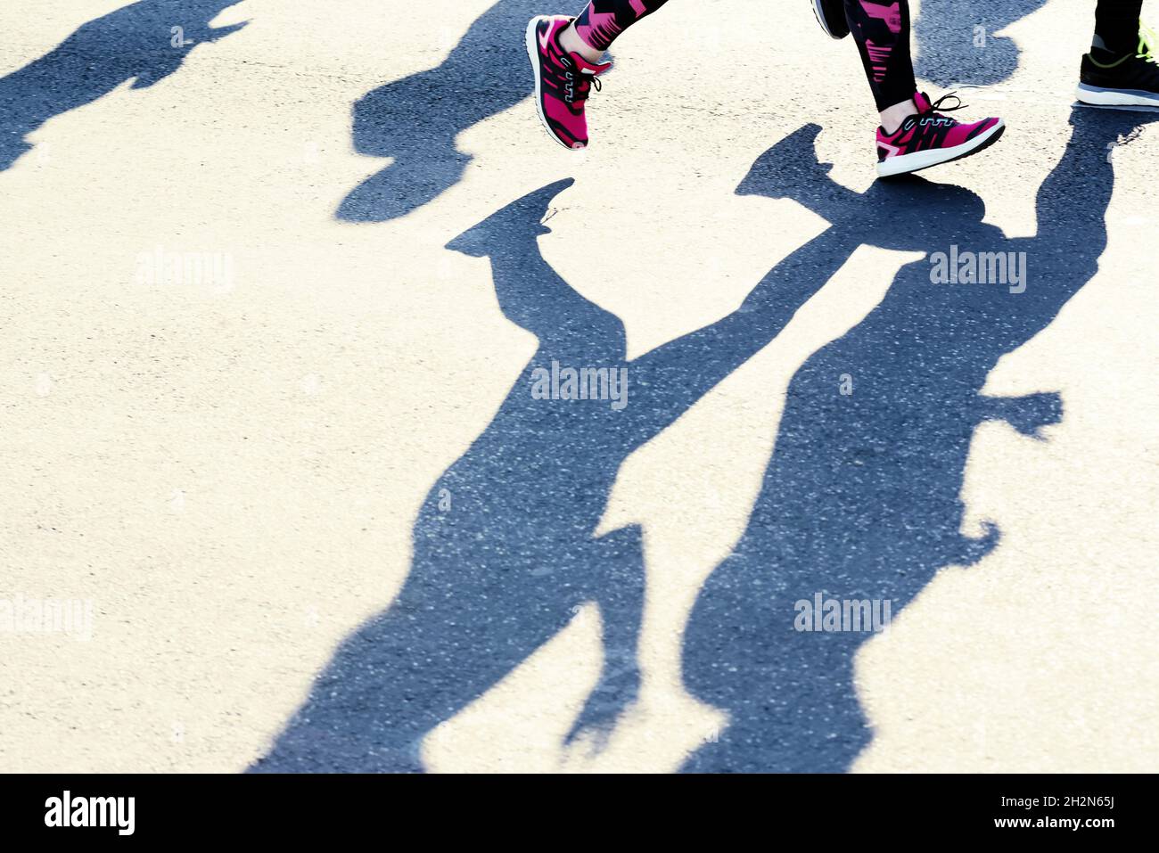 Füße und Schatten von laufenden Menschen Stockfoto