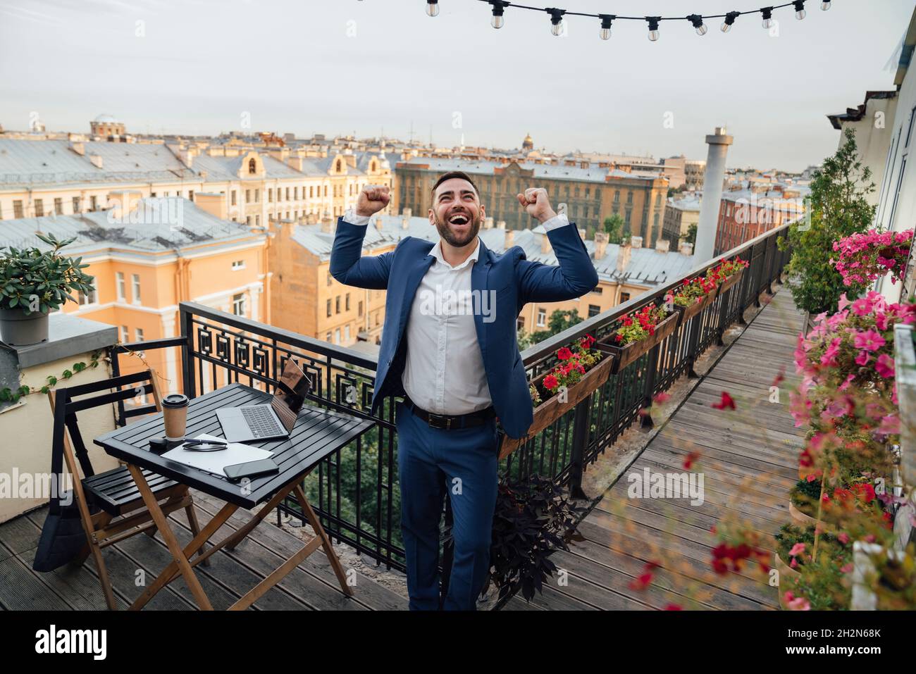 Fröhlicher Geschäftsmann, der auf dem Bürobalkon aufsteht und aufschaut Stockfoto