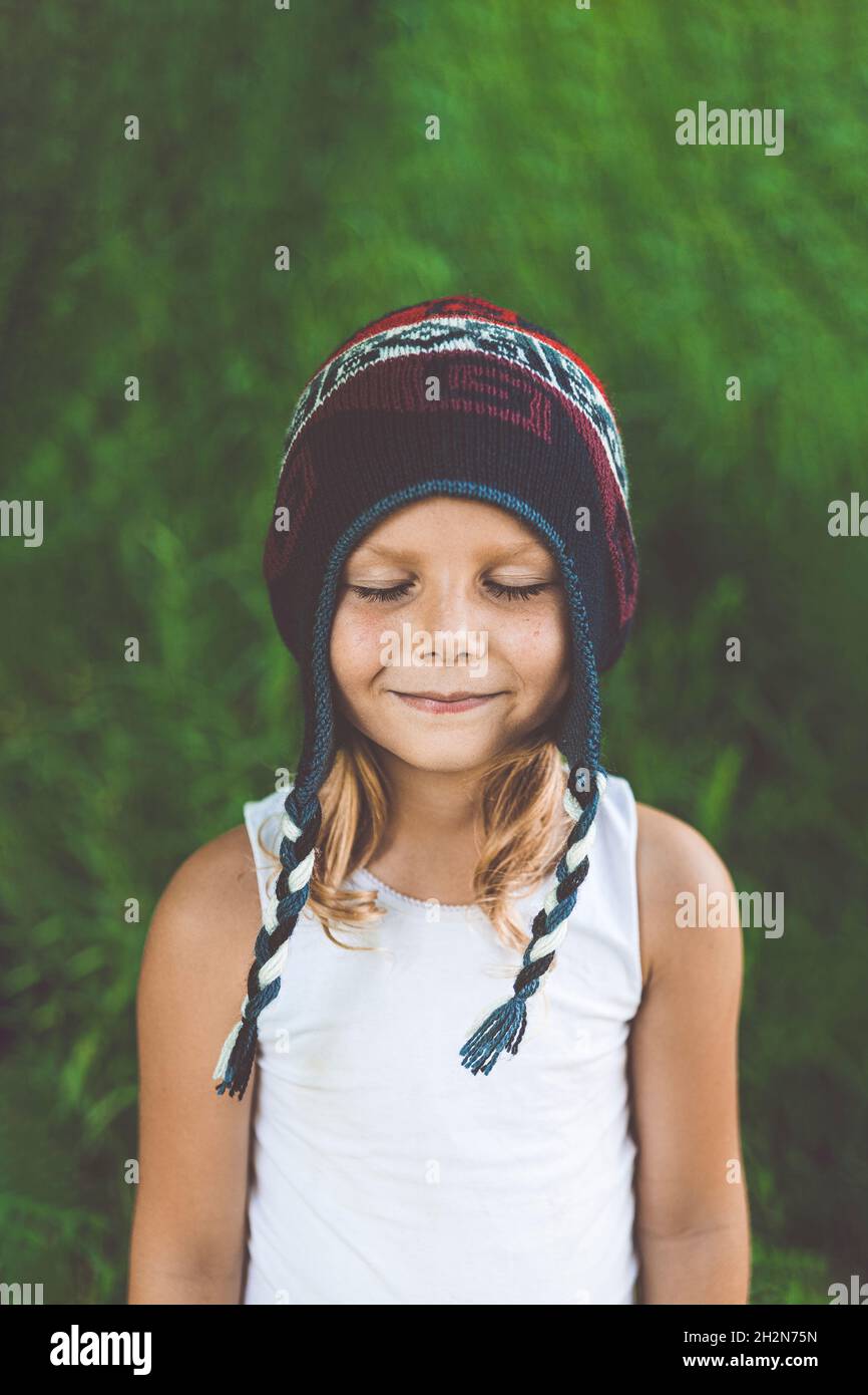 Nettes Mädchen mit gestrickten Hut stehend mit geschlossenen Augen Stockfoto