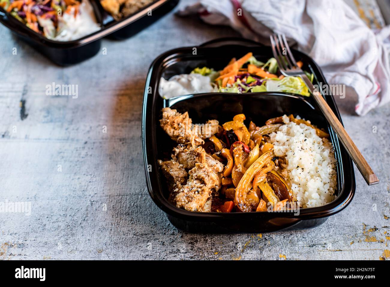Verzehrfertige Fajita-Schüssel mit Huhn, Salat, gebratener Paprika und Blumenkohlereis Stockfoto