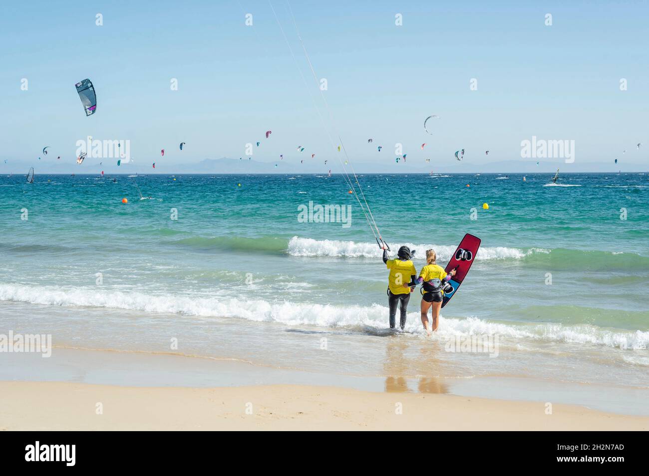 Weibliche Trainerin mit Kiteboard, die Frau an sonnigen Tagen anweist Stockfoto