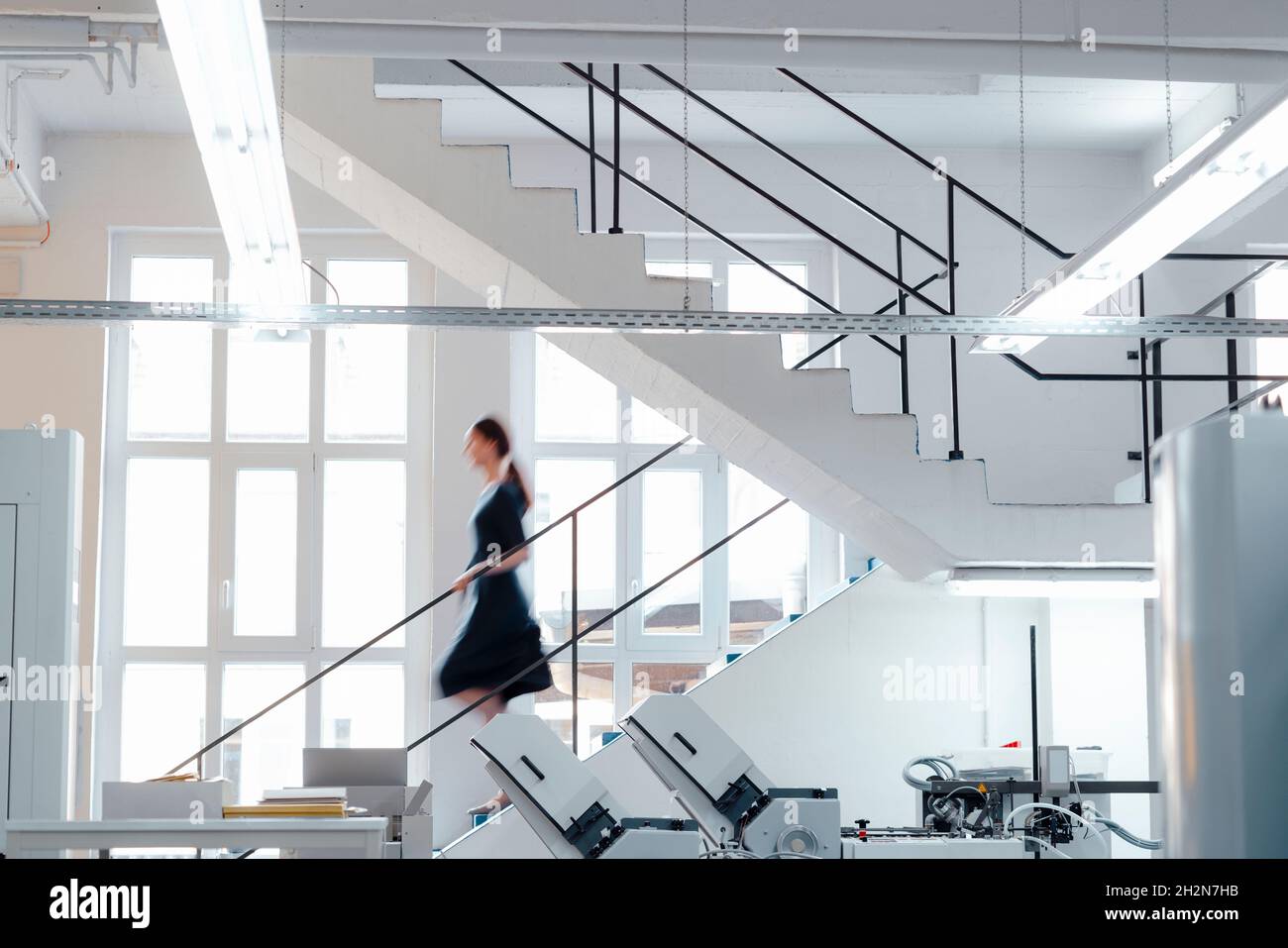 Geschäftsfrau, die sich in der Werkstatt auf der Treppe nach unten bewegt Stockfoto