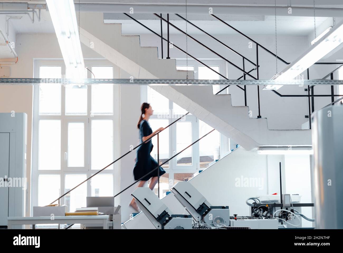 Geschäftsfrau, die in der Werkstatt auf der Treppe aufsteht Stockfoto
