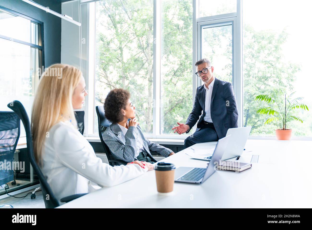 Weibliche Geschäftsleute hören männlichen Kollegen während der Besprechung im Büro zu Stockfoto