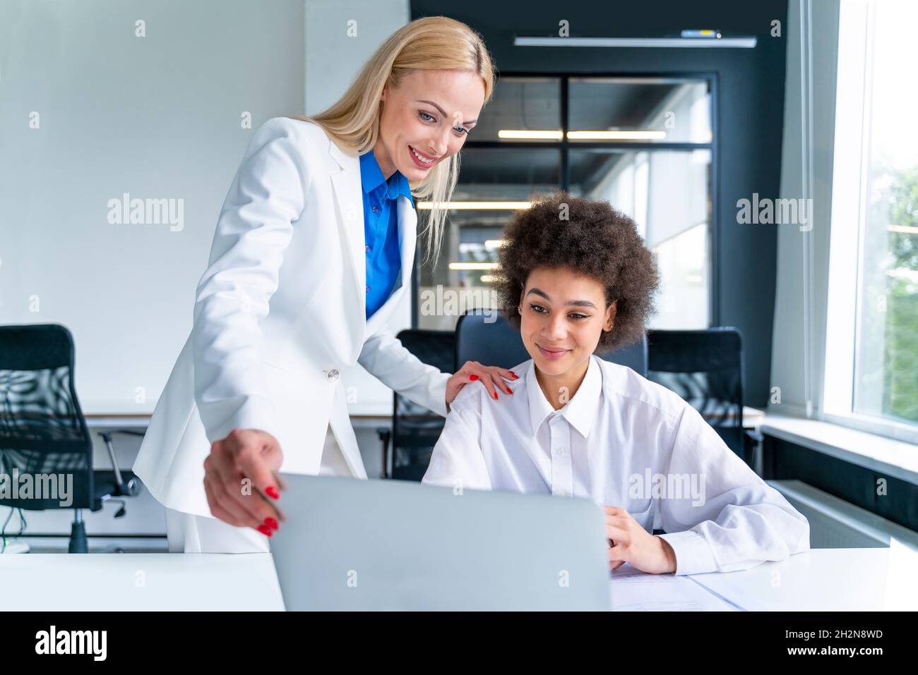 Weibliche Geschäftsleute, die sich am Arbeitsplatz einen Laptop teilen Stockfoto
