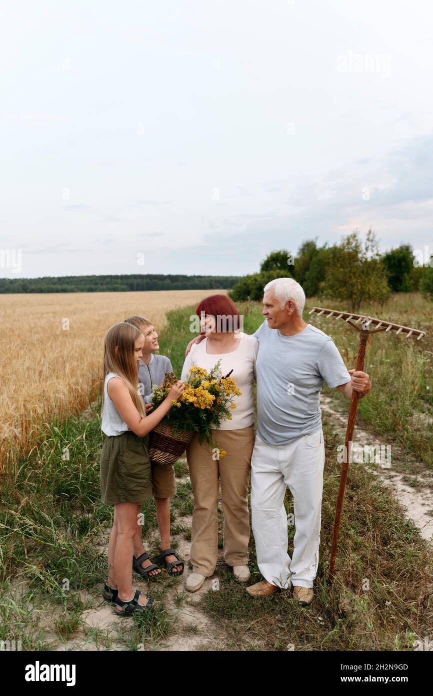 Multi-Generationen-Familie mit blühenden Blumen und Gartengeräte auf dem landwirtschaftlichen Feld Stockfoto