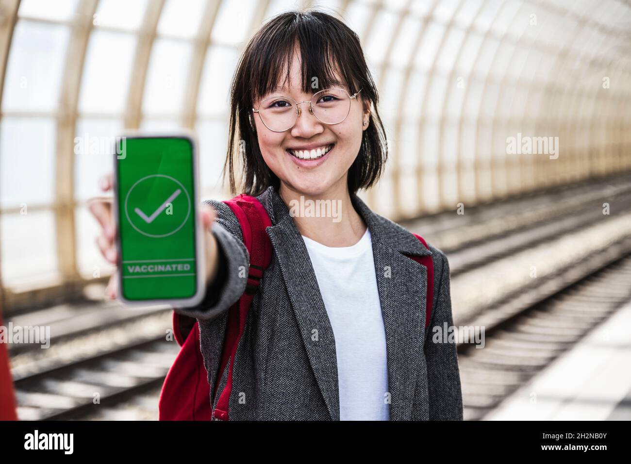 Lächelnde Frau mit Impfpass an der U-Bahn-Station Stockfoto