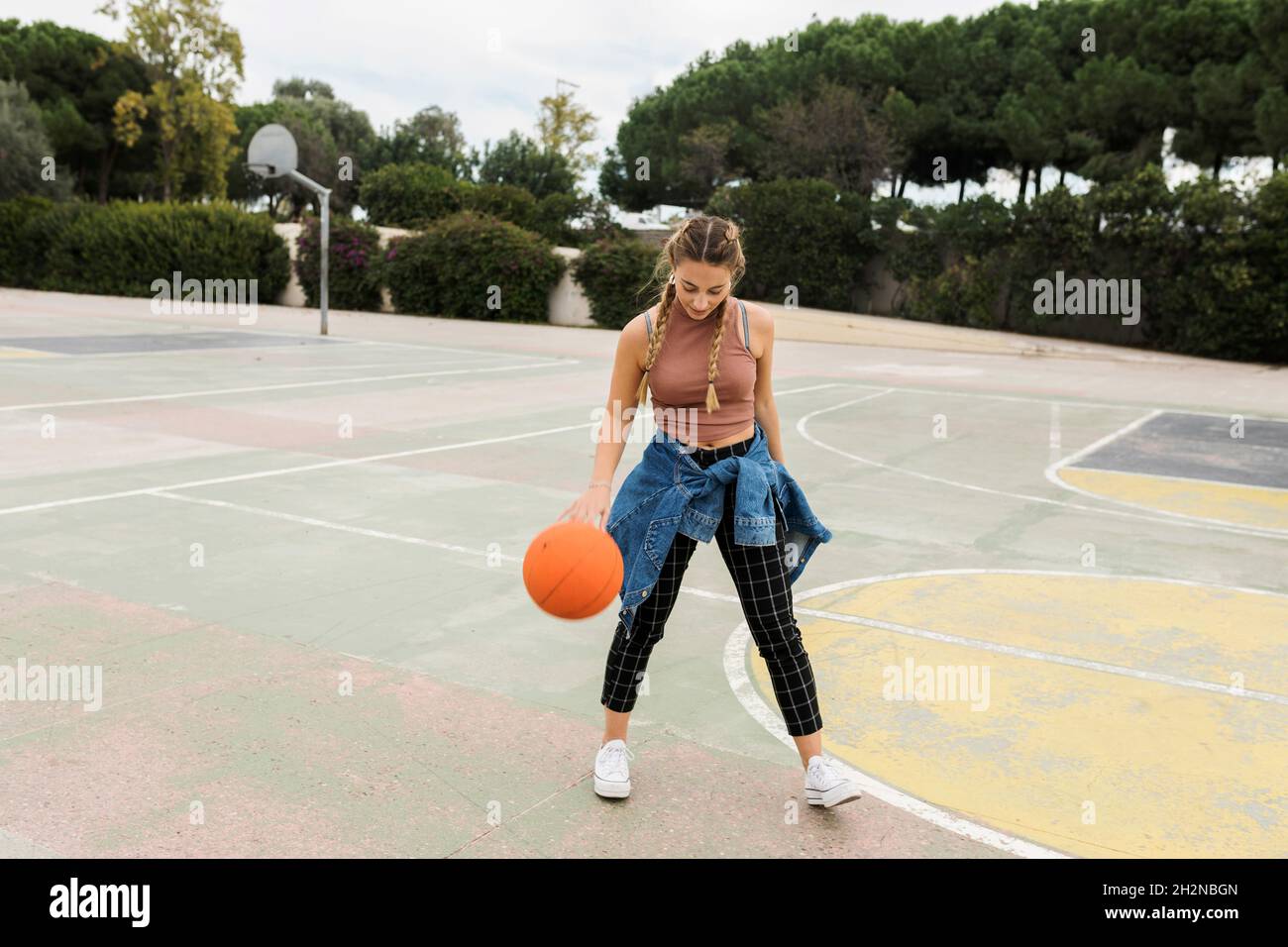 Frau, die auf dem Sportplatz mit Basketball spielt Stockfoto