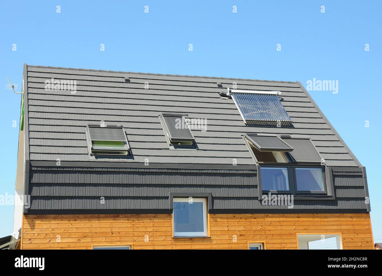 Modernes Hausdach mit Solar Water Heater, Sonnenkollektoren und Oberlichter. Schönes neues modernes Haus mit Sonnenkollektoren, Oberlichtern und Dormer. Modder Stockfoto