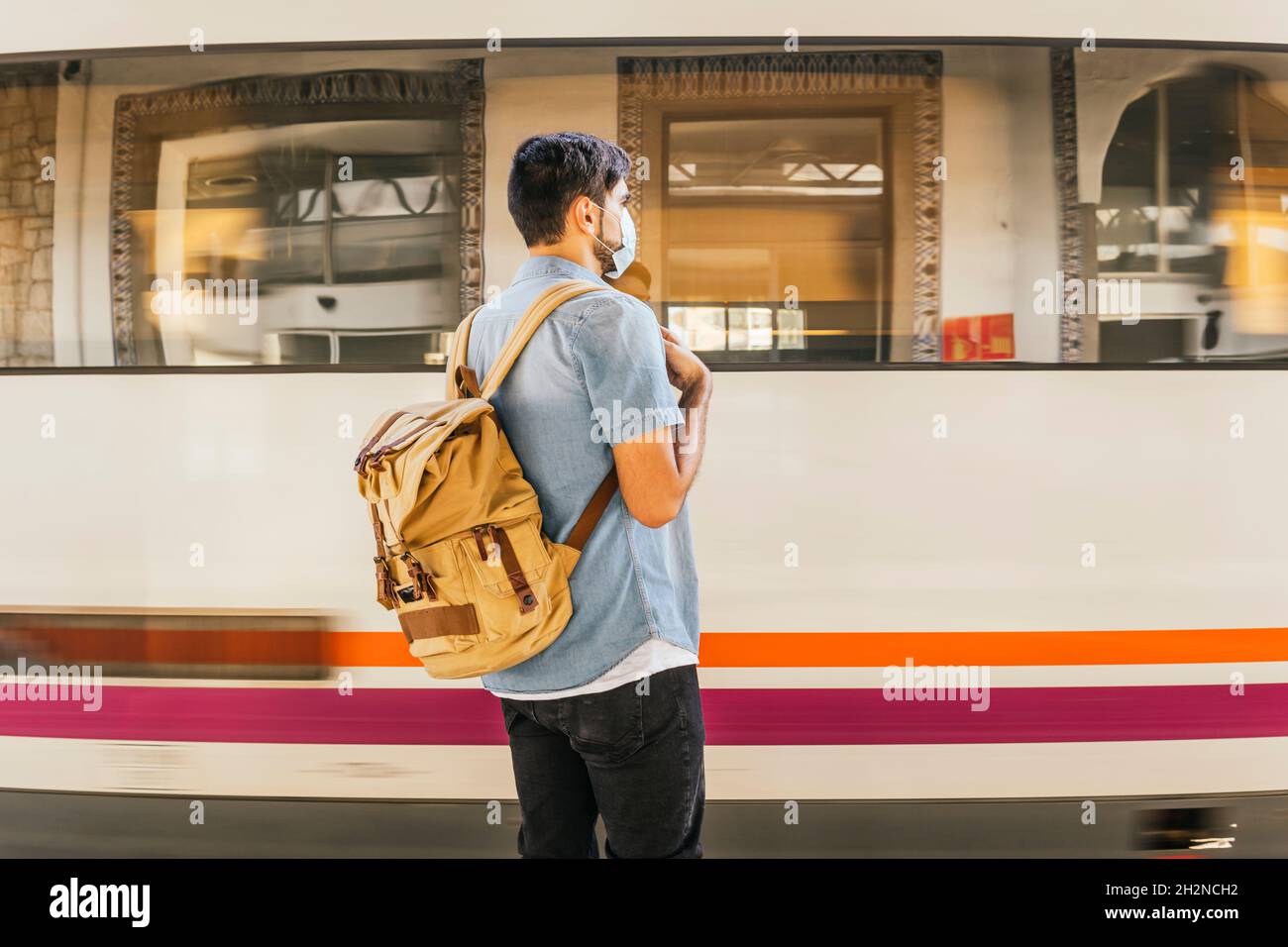 Mann mit Rucksack wartet auf den Zug am Bahnhof Stockfoto