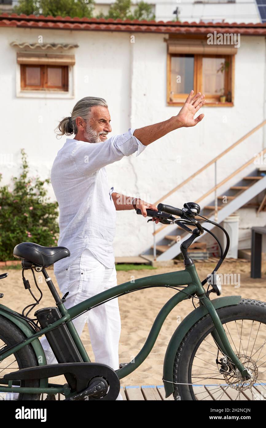 Lächelnder Mann mit dem Fahrrad winkende Hand Stockfoto