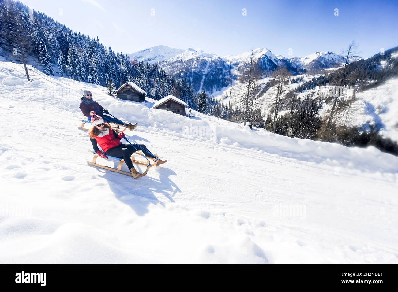 Paar ziehen Rodel beim Wandern auf Schnee an sonnigen Tagen Stockfoto