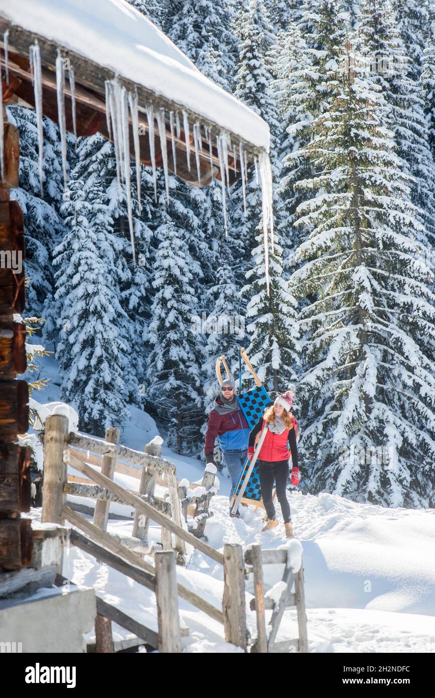 Frau zeigt, während sie einen Mann auf Schnee mit dem Schlitten hält Stockfoto