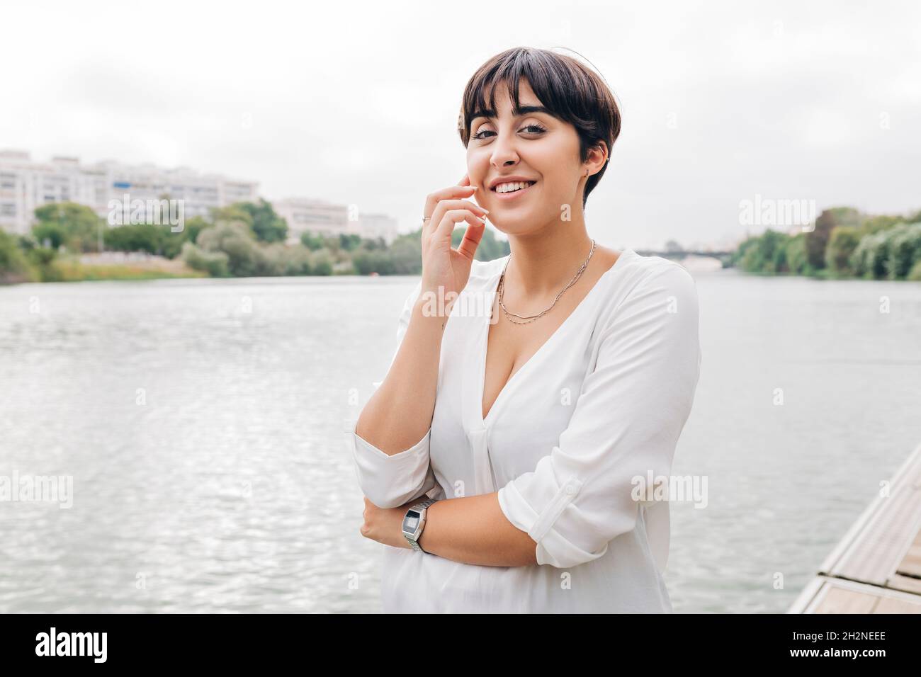 Schöne Frau mit kurzen Haaren, die am See steht Stockfoto