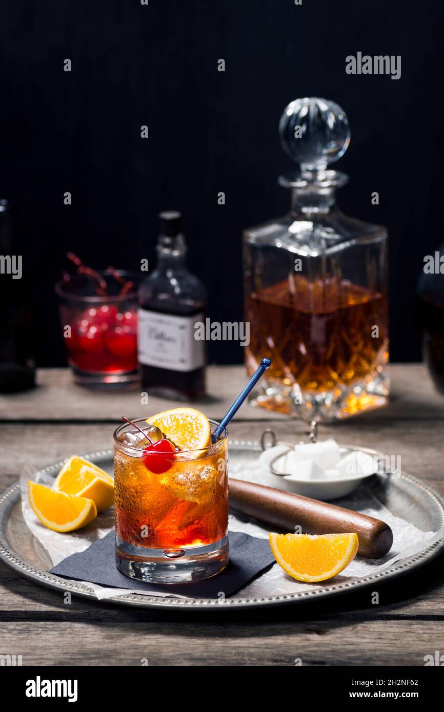 Altmodischer Cocktail aus Rocks Glass mit Zutaten und Bar-Tools in der dunklen Vintage-Holzbar Stockfoto