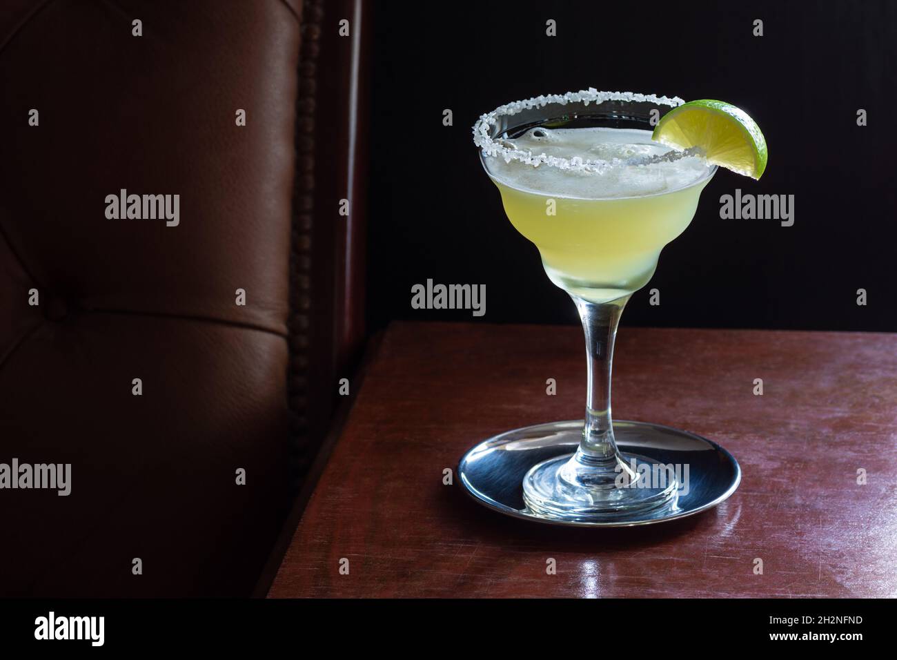 Klassisches Margarita Cocktail-Getränk, serviert mit gesalzenem Rand und Limette in Glas in einer dunklen luxuriösen Bar Stockfoto
