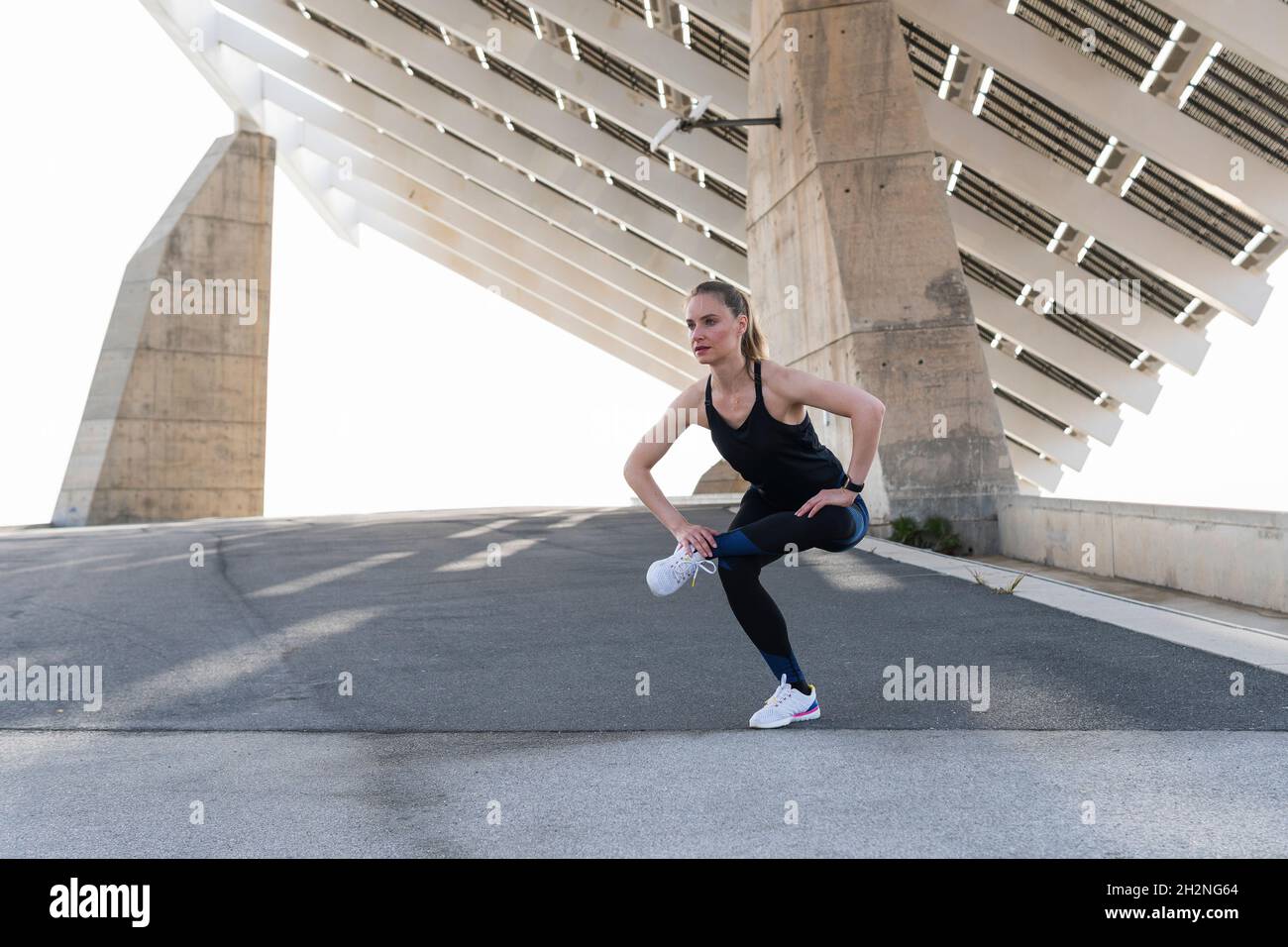 Weibliche Athletin wärmt sich beim Stretching auf der Straße auf Stockfoto