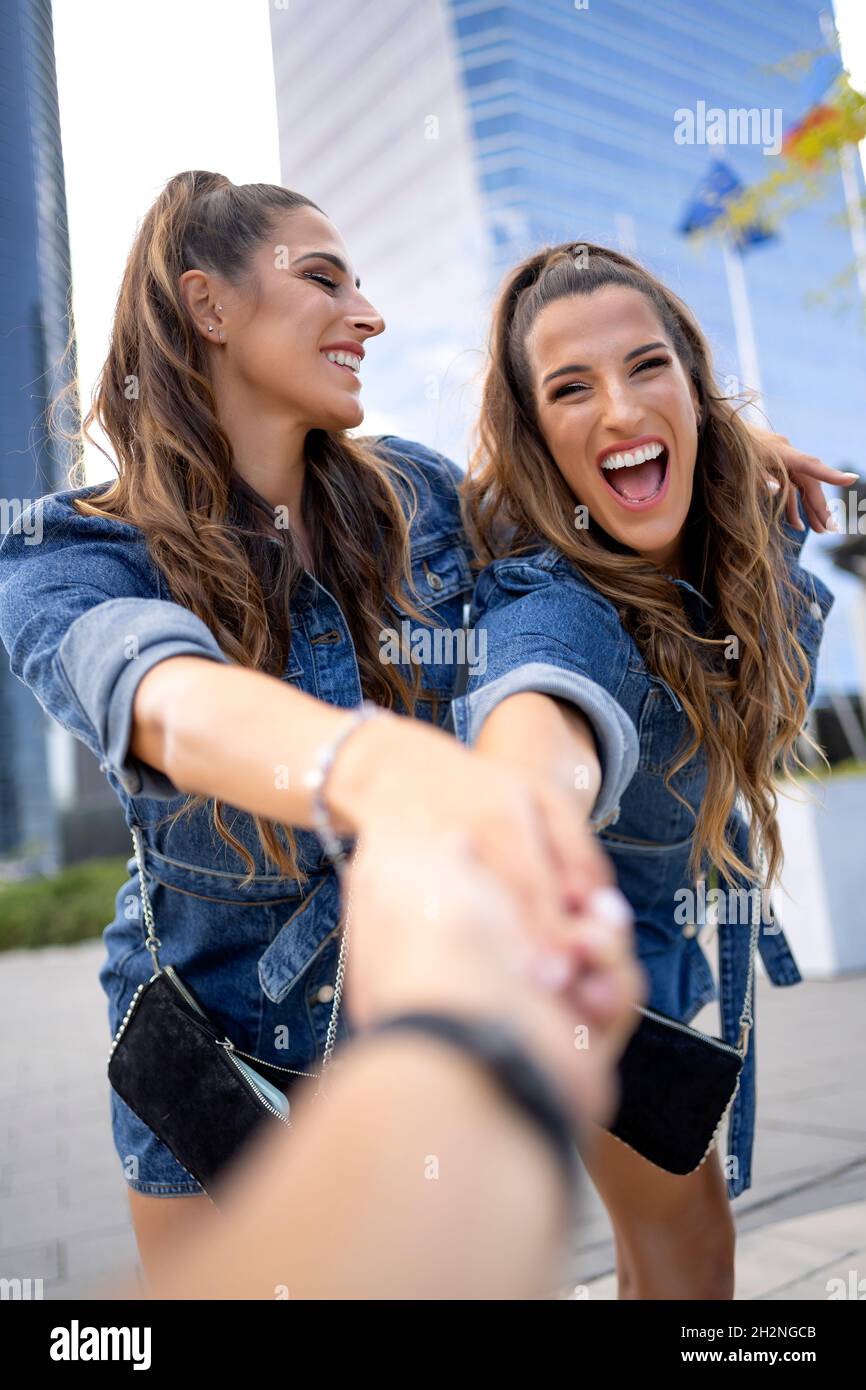 Glückliches Weibchen identischen Zwilling hält Hand von Freund Stockfoto