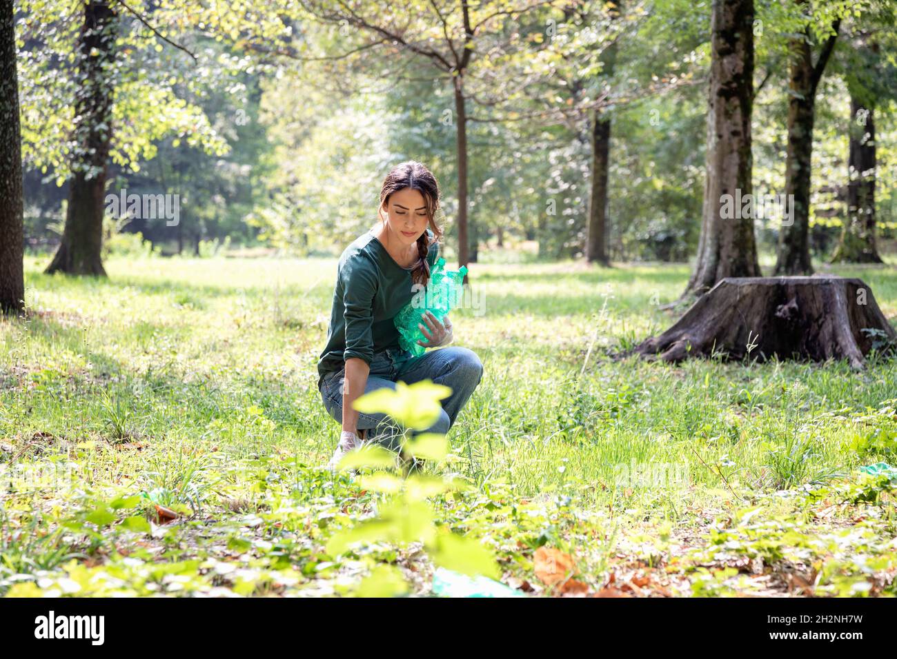 Weibliche Freiwillige, die Plastikflaschen im Park abholt Stockfoto