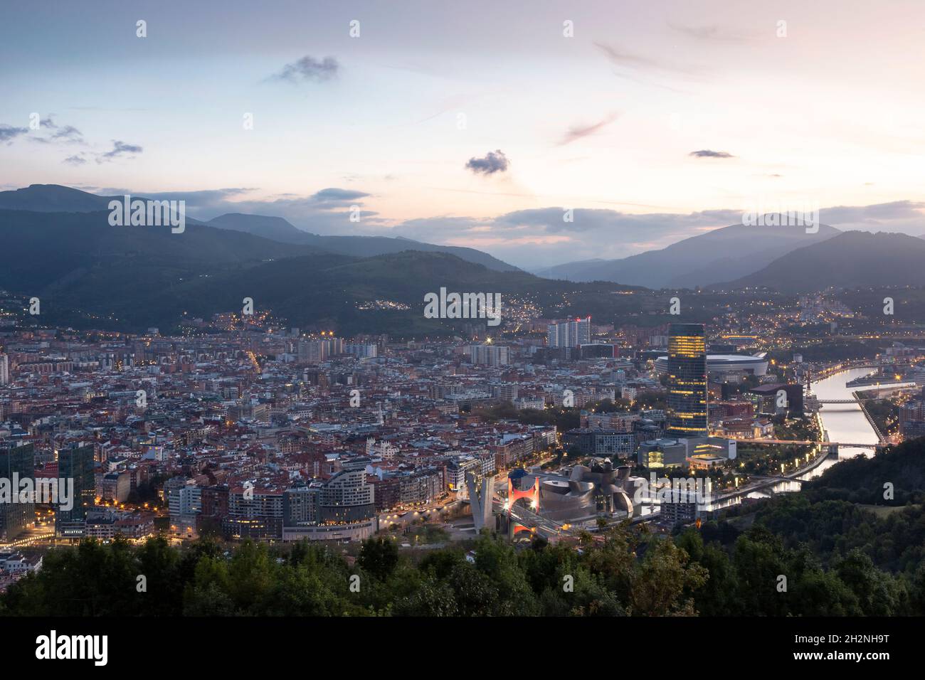 Spanien, Biskaya, Bilbao, Riverside City in der Abenddämmerung Stockfoto