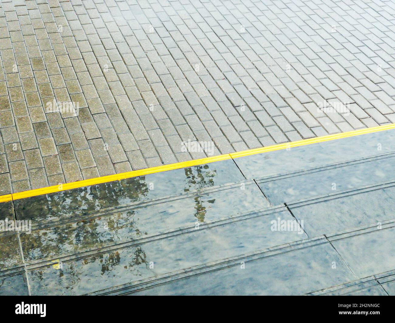 Nasser Bürgersteig und graue Granittreppe mit Spiegelung von Baum. Städtischer regnerischer Hintergrund. Stockfoto