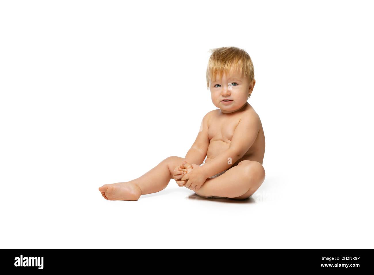 Porträt von kleinen niedlichen Kleinkind Junge, Baby in Windel spielen und lachen isoliert über weißen Studio-Hintergrund. Ernsthaftes Kind Stockfoto