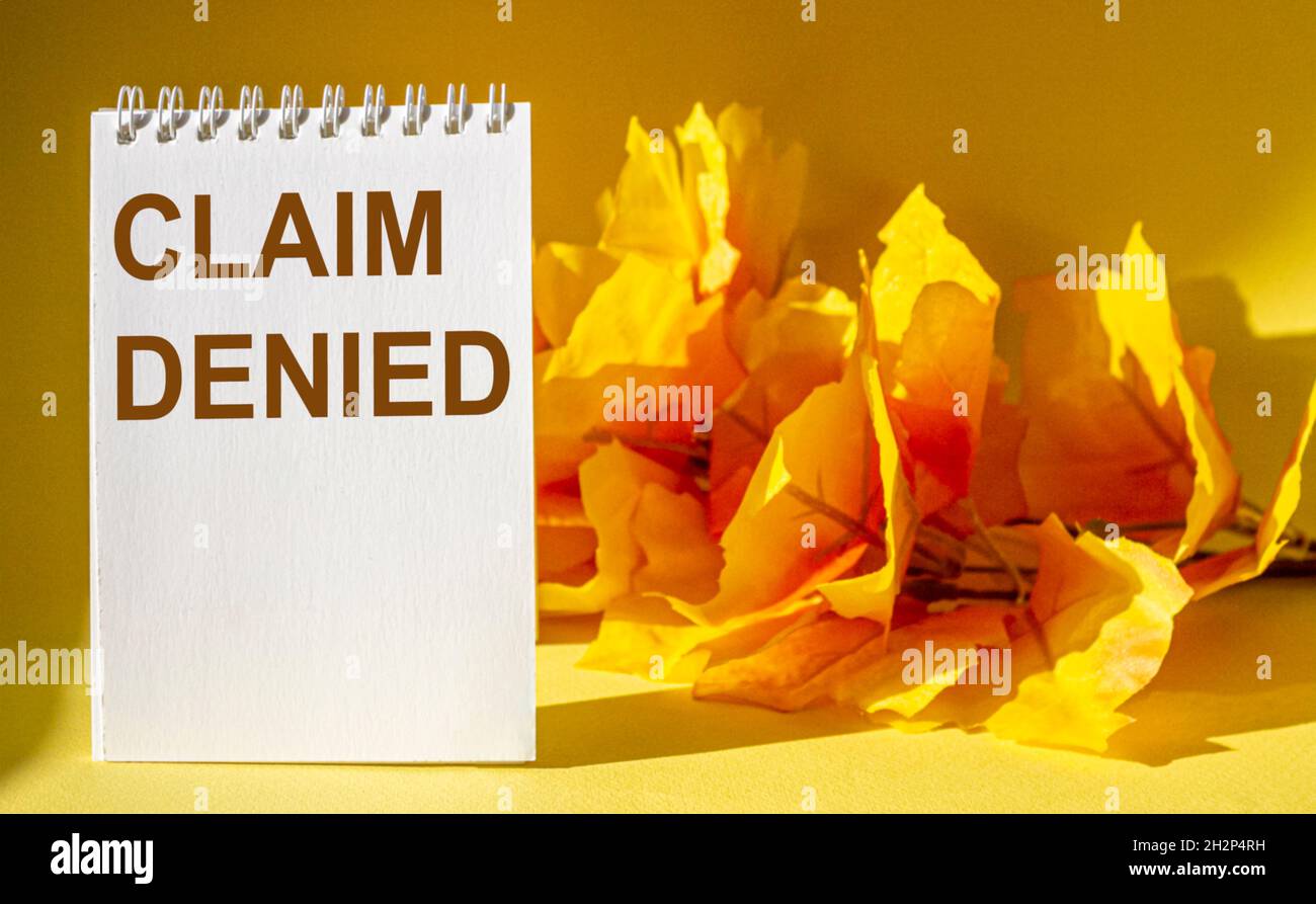 Der Satz, der abgelehnt wurde, steht auf einem Notizbuch und einem gelben Tisch mit Laub im Hintergrund. Stockfoto
