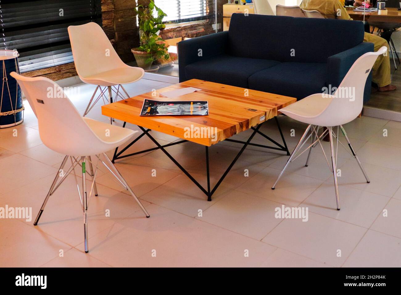 Schönes Bild von weißen eames vitra Stühlen und einem blauen Zweisitzer-Sofa im Loungebereich Stockfoto