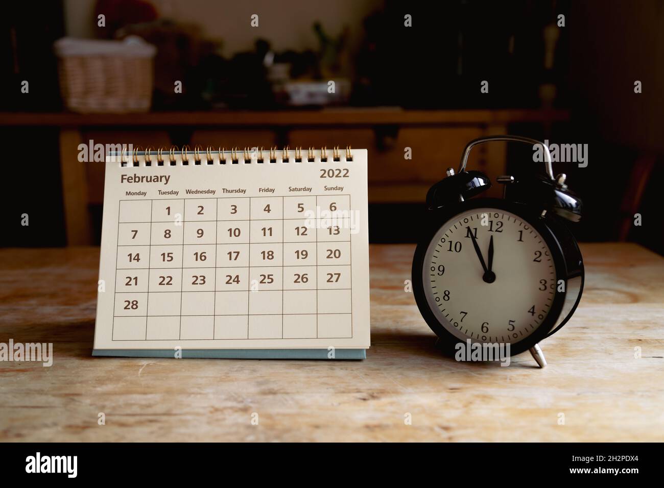 Kalender vom 2022. Februar und schwarze Vintage-Uhr auf Holztisch Stockfoto