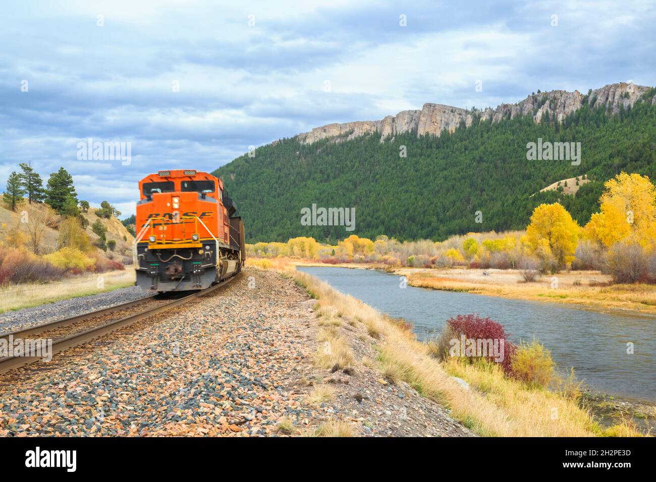 Der Zug fährt vorbei an Klippen und Herbstfarben entlang des clark Fork River in der Nähe von drummond, montana Stockfoto