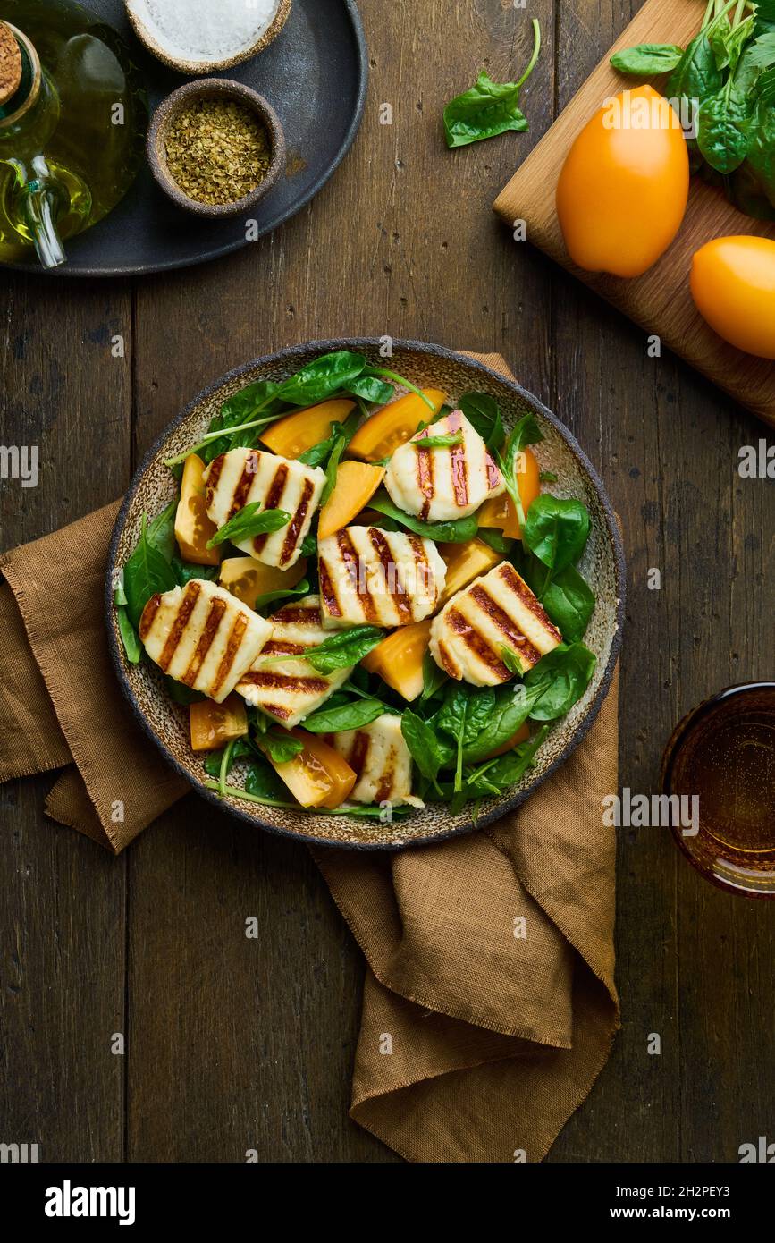 Leckerer Salat mit Orangentomaten, circassian Halloumi-Käse, Spinat, Olivenöl und Gewürzen Stockfoto