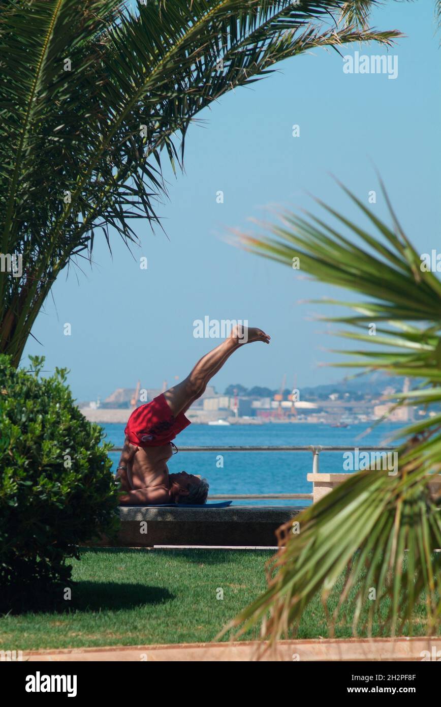 Europa, Spanien, Balearen, Mallorca, Palma, Mann macht Joga-Übung an der Strandpromenade von Palma, Badia de Palma Stockfoto