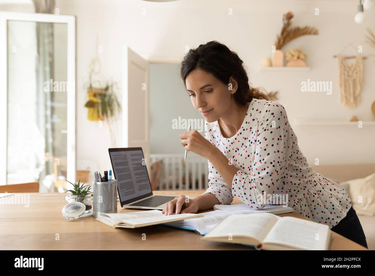 Fokussierte Erwachsene Studentin, die Hausaufgaben macht, Bücher am Laptop liest Stockfoto