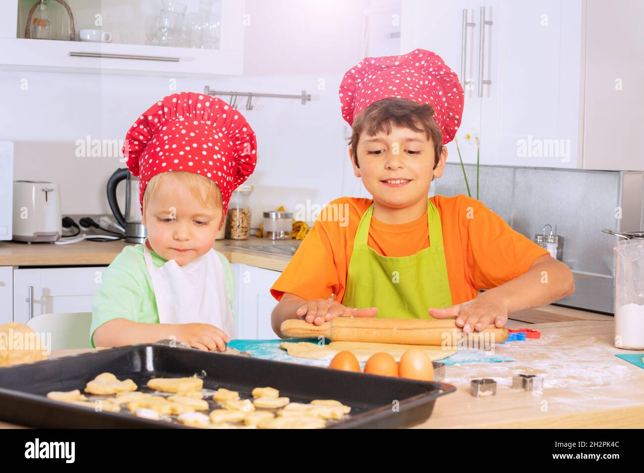 Zwei Jungen backen in der Küche und legen Teigformen auf das Tablett Stockfoto