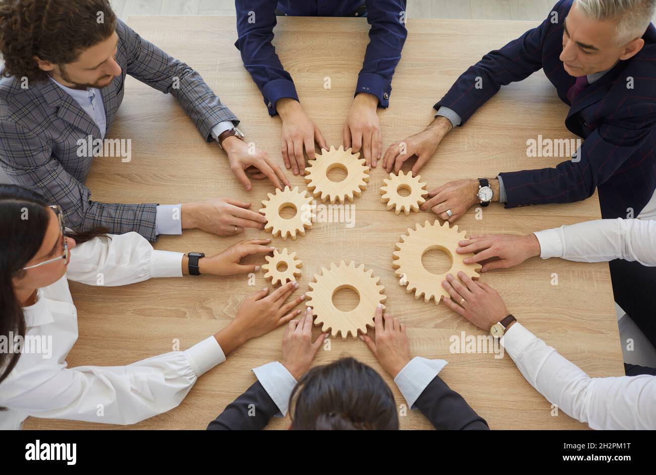 Team von Geschäftsleuten, die Zahnräder verbinden, um das Konzept der Teamarbeit zu veranschaulichen Stockfoto