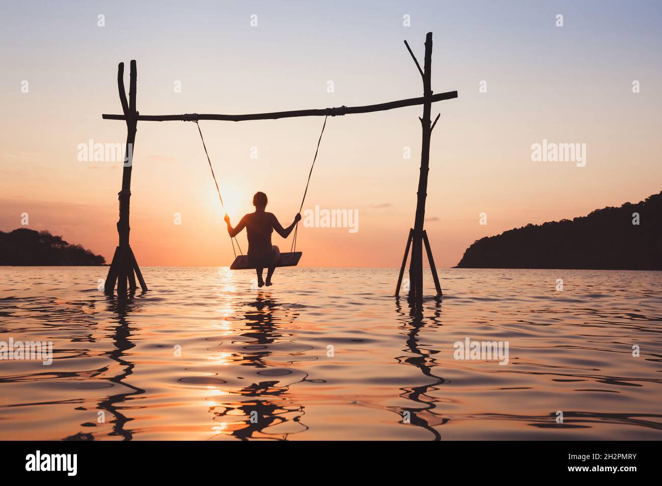 Strandurlaub am Meer bei Sonnenuntergang, Urlaub auf paradiesischer tropischer Insel, Silhouette der Frau auf Seilschaukel im Wasser Stockfoto Strandurlaub am Meer bei Sonnenuntergang, Urlaub auf paradiesischer tropischer Insel, Silhouette der Frau auf Seilschaukel im Wasser Stockfoto