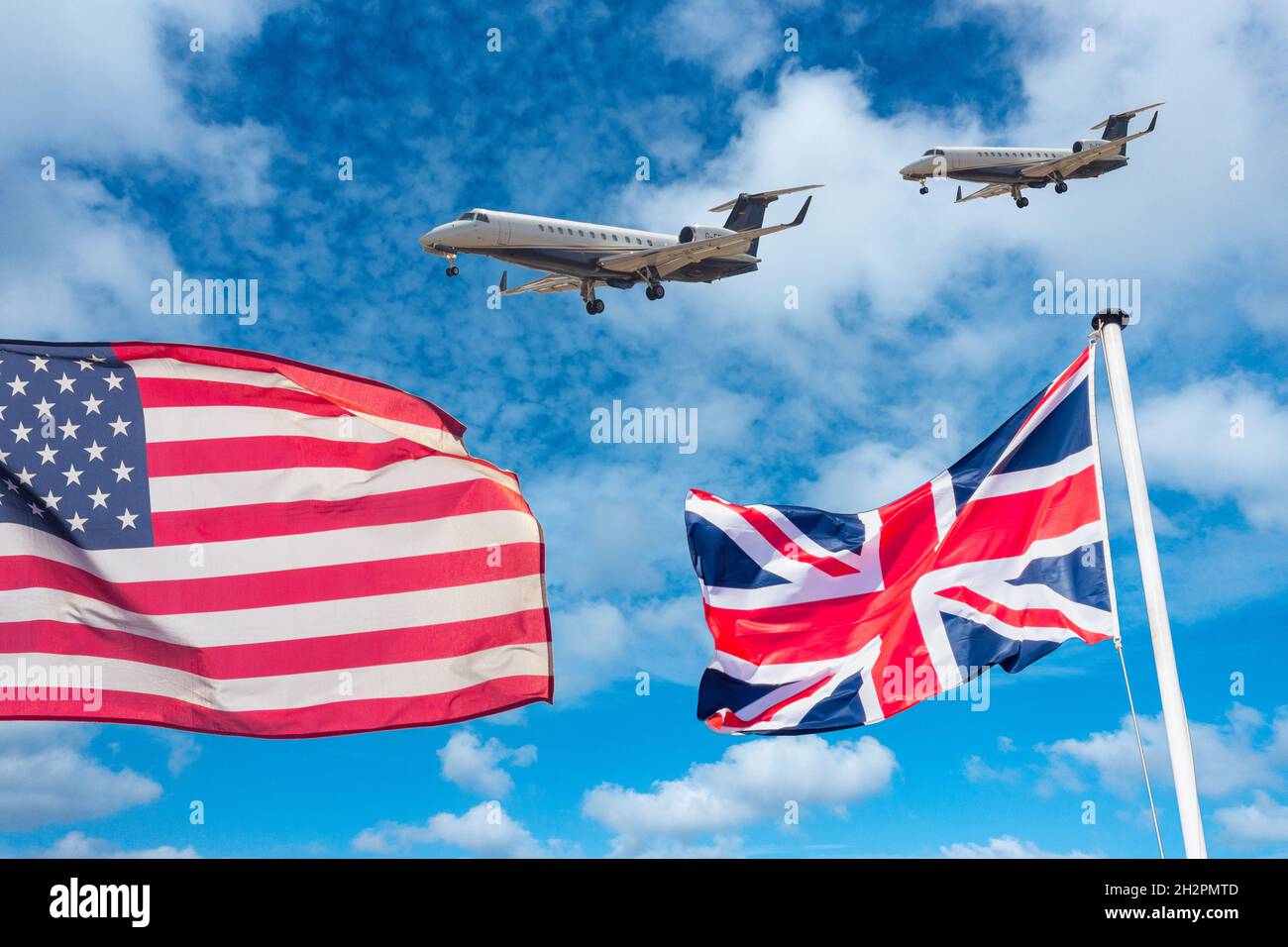 Flaggen der USA und Großbritanniens mit Privatjets vor blauem Himmel. Luftfahrtindustrie, globale Erwärmung, Handelsabkommen, Luftverschmutzung, Flugverbot für Covid... Konzept. Stockfoto