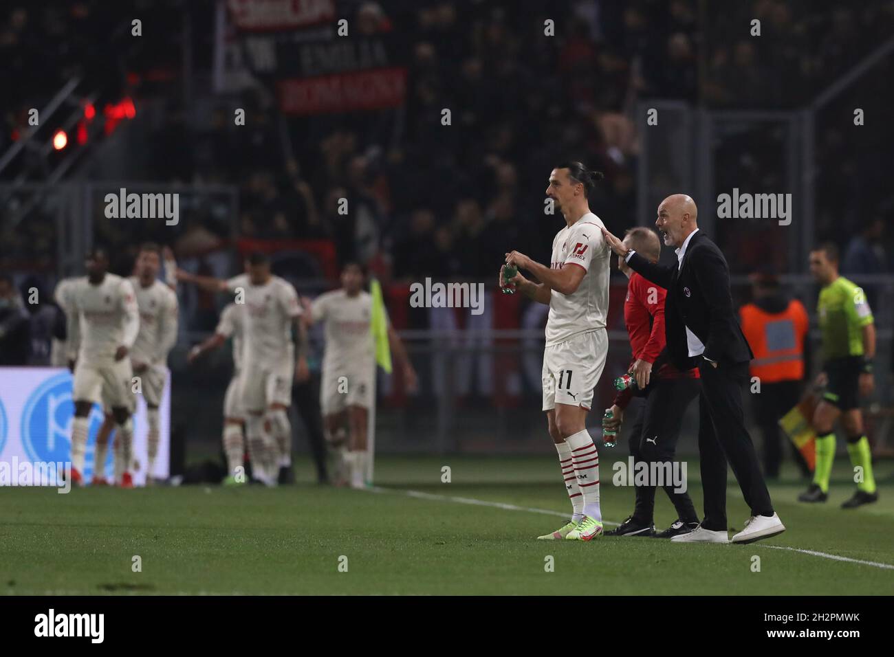 Bologna, Italien, 23. Oktober 2021. Stefano Pioli Cheftrainer des AC Mailand gibt Zlatan Ibrahimovic vom AC Mailand Anweisungen, während die Spieler im Hintergrund nach Rafael Leaos Tor feiern, das der Mannschaft während des Serie-A-Spiels in Renato Dall'Ara, Bologna, eine Führung von 1-0 gab. Bildnachweis sollte lauten: Jonathan Moscrop / Sportimage Stockfoto