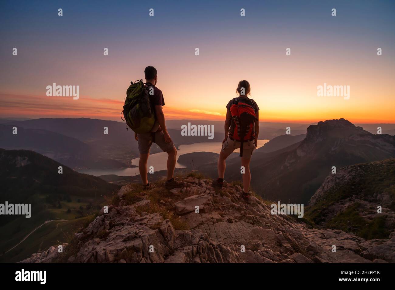 Reisen Sie in die Alpen, Touristen Wanderer mit Rucksäcken bei Sonnenuntergang genießen Panoramablick Stockfoto