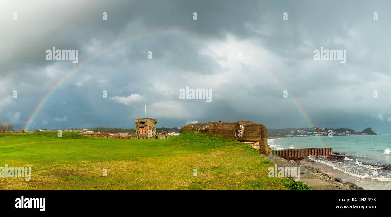 Regenbogen über Beton nazi-Bunker aus dem Zweiten Weltkrieg an der Küste mit Fort Henry im Hintergrund, Vogtei von Jersey, La Manche, Channel Islands, Großbritannien Stockfoto