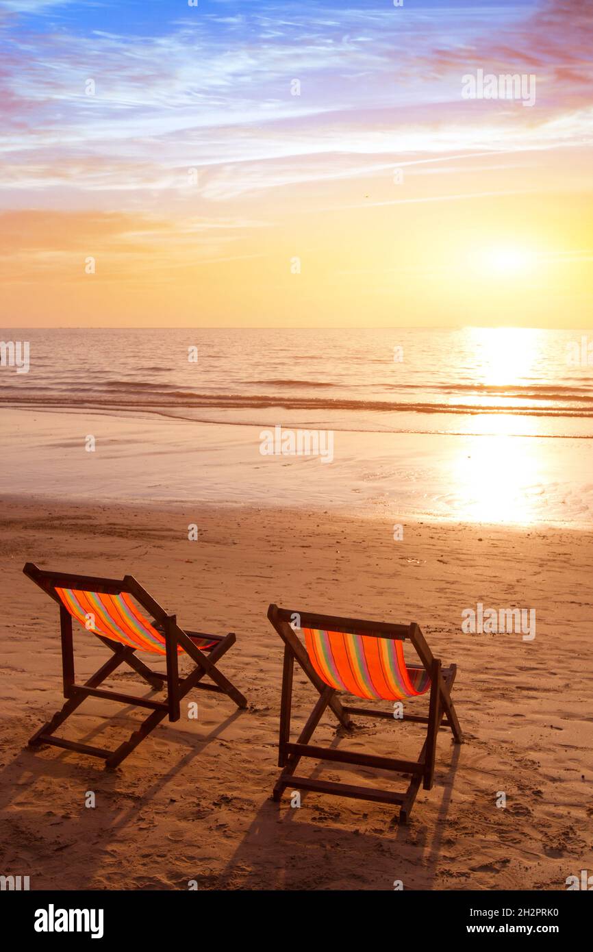 Strandurlaub vertikaler Hintergrund, romantischer Kurzurlaub an der tropischen Küste, zwei Liegestühle im Hotel für Paare Stockfoto Strandurlaub vertikaler Hintergrund, romantischer Kurzurlaub an der tropischen Küste, zwei Liegestühle im Hotel für Paare Stockfoto