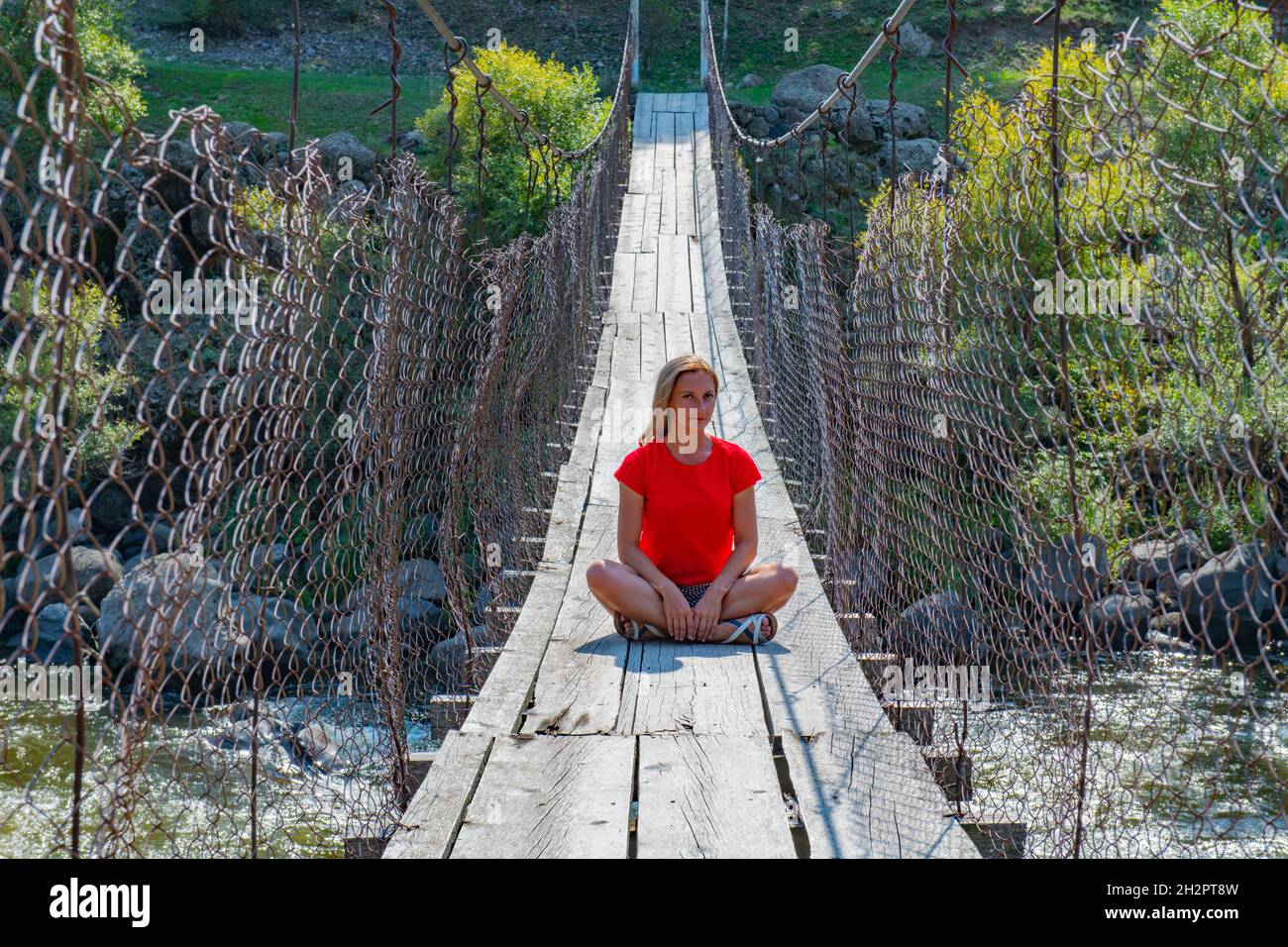 In Rot sitzt eine Frau auf der Unterweltbrücke in georgien Stockfoto