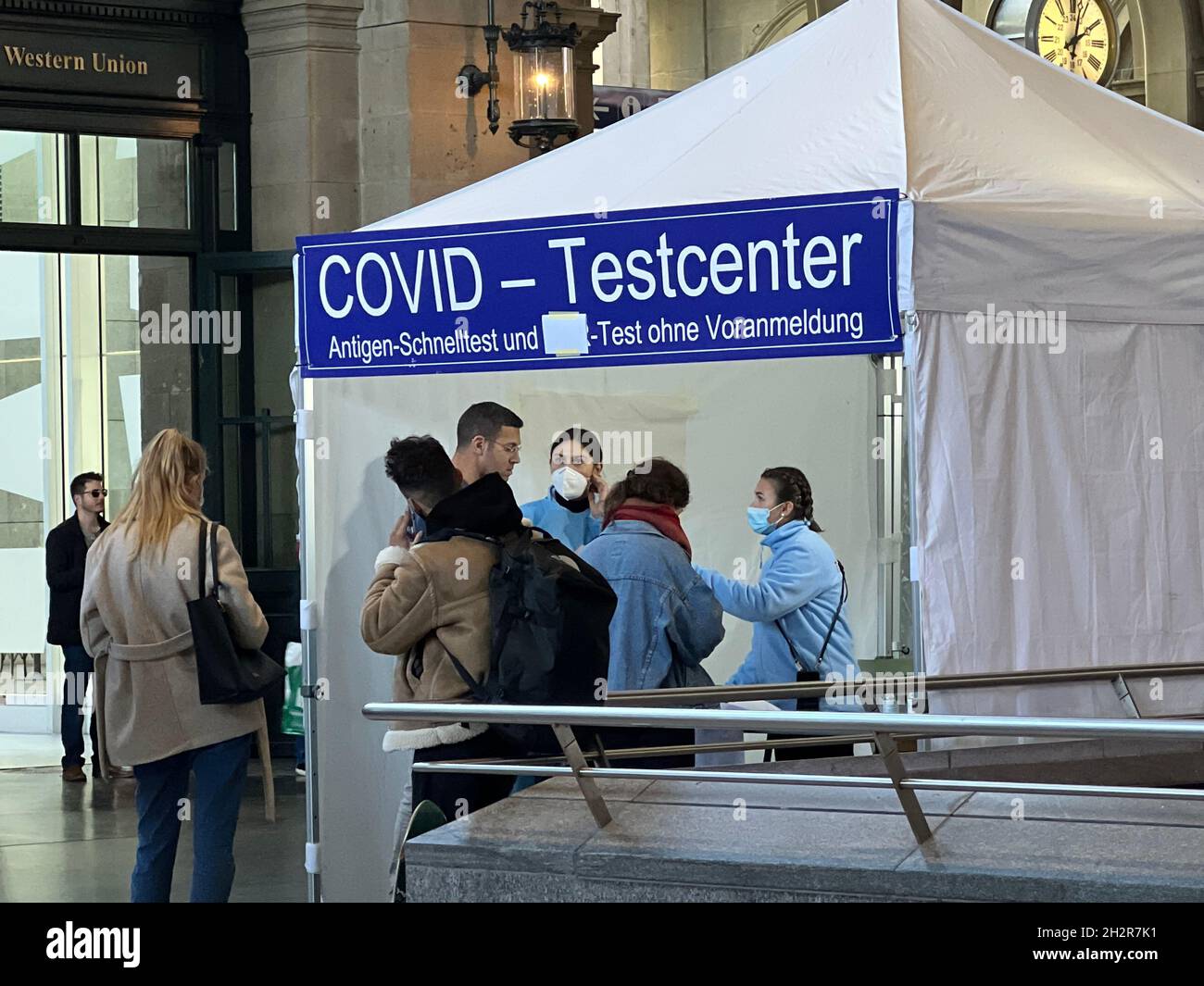 Covid-Testzentrum am Hauptbahnhof in Zürich. Eine deutsche Aufschrift besagt, dass für den Speed-Antigen-Test kein Termin erforderlich ist. Personen in der Warteschlange. Stockfoto