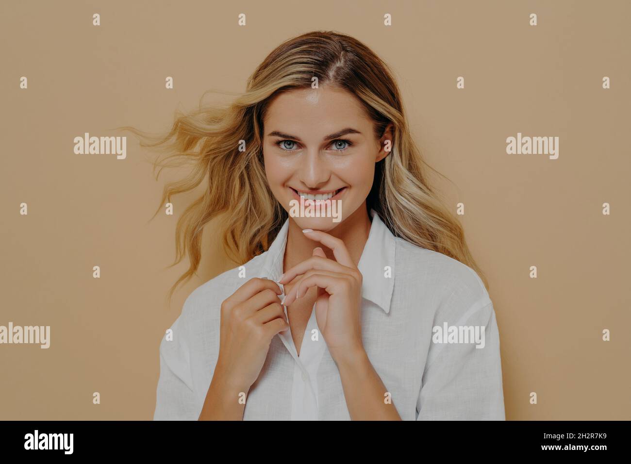 Flirty romantisch und feminin schöne blonde Frau Blick auf die Kamera mit hellen breiten Lächeln Stockfoto