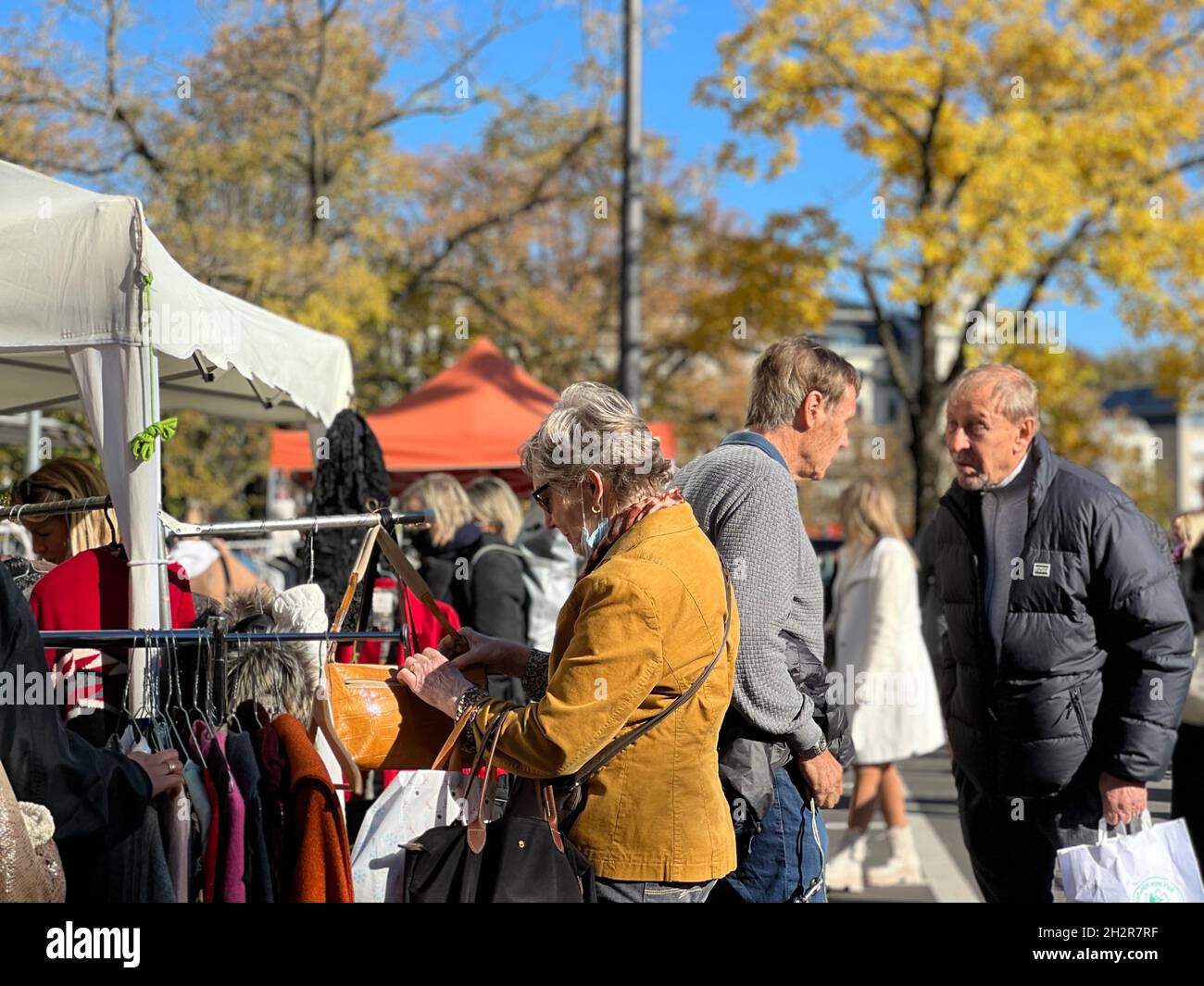 Menschen auf dem Flohmarkt in Zürich am Samstag im Oktober. Eine Frau inspiziert eine Tasche und zwei Männer sprechen zusammen. Pople und Marktstände. Stockfoto