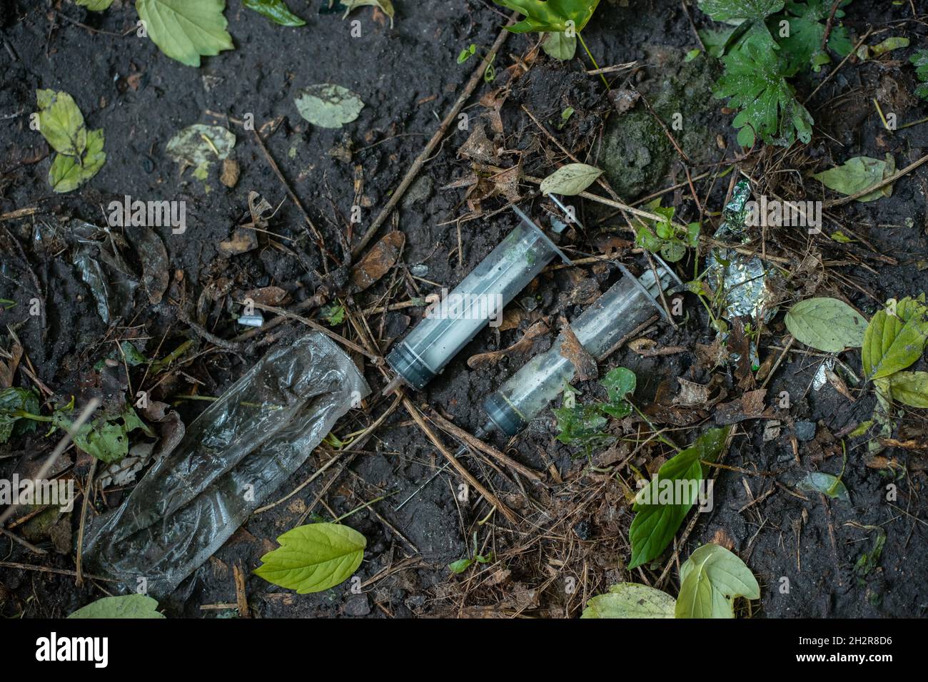 Ein Haufen von gebrauchten schmutzigen Spritzen, die nach der Medikamenteninjektion auf dem Boden im Freien lagen, war ausgezogen Stockfoto