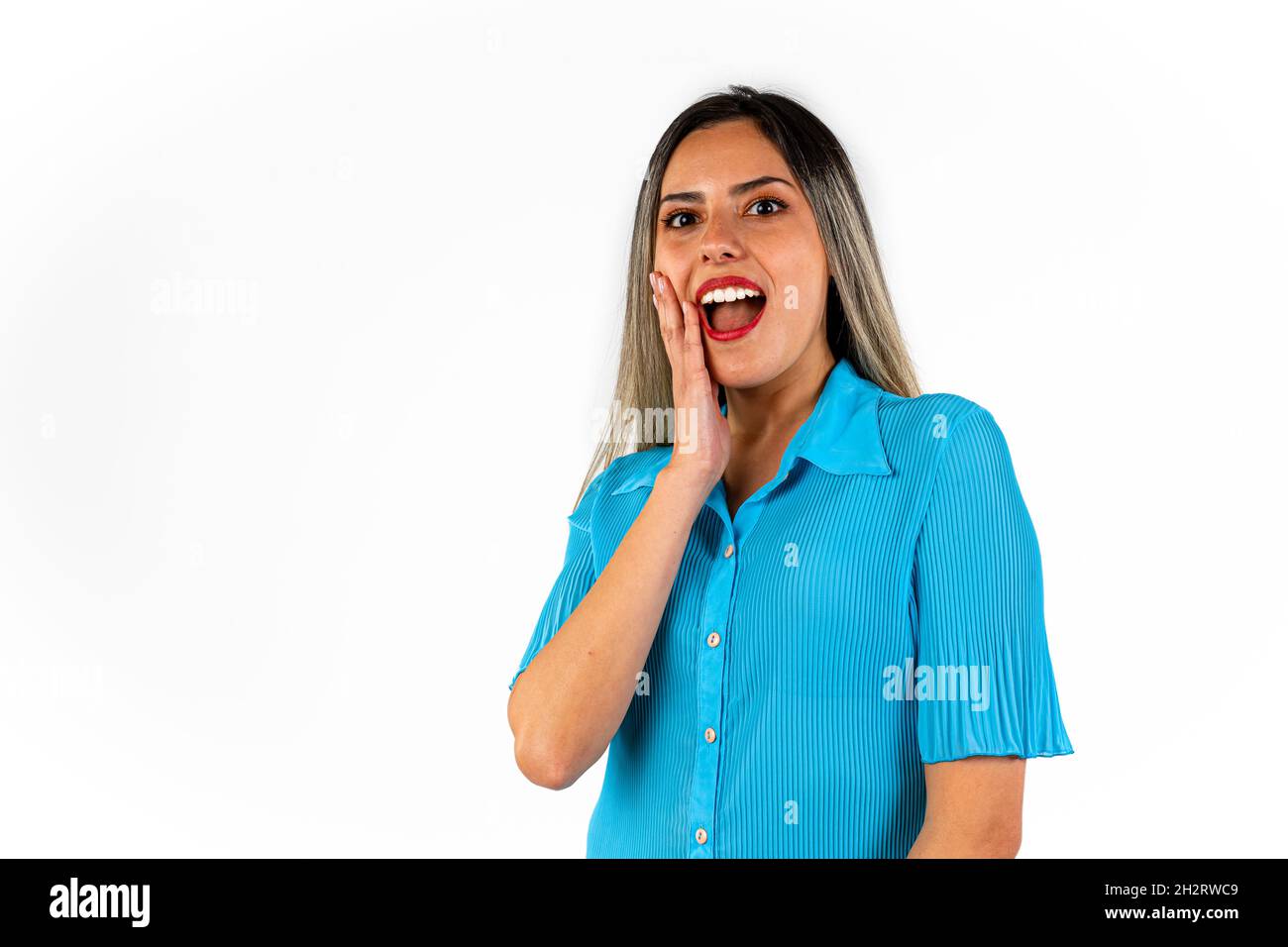 Ein Porträt einer schönen jungen Frau, eine Hand auf der Wange und ein überraschter Gesichtsausdruck. Stockfoto