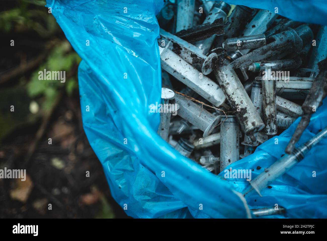 Müllbeutel mit gebrauchter medizinischer Einwegspritze, die von Drogenabhängigen im Park freigesetzt wurde Stockfoto